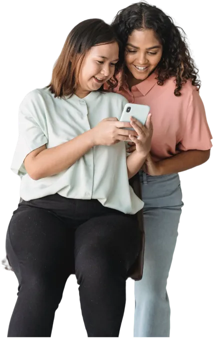 Two young women smiling together while looking at a phone